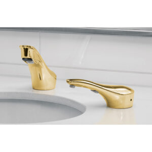 Bathroom sink with gold faucets on white countertop and backsplash.