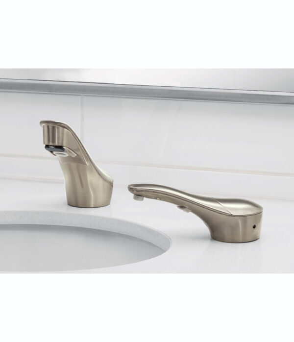 Modern brushed metal bathroom faucet, separate handle, white countertop, tiled backsplash.