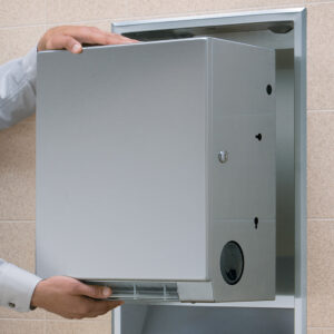 Person handling a stainless steel hand dryer in a recessed wall compartment.