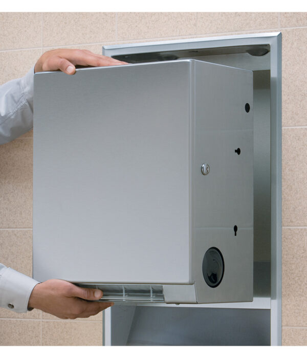 Person handling a stainless steel hand dryer in a recessed wall compartment.