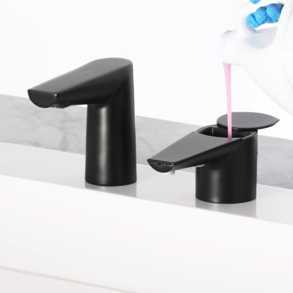 Black soap dispensers on a counter, one being filled with pink soap from a white container.