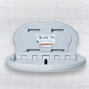 Wall-mounted gray baby changing station with safety instructions and diagrams visible.