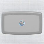 Wall-mounted baby changing station with gray cover and logo, tiled wall background.