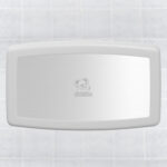 Wall-mounted horizontal baby changing station with central logo on tiled surface.