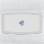 Wall-mounted baby changing station with Koala Kare logo on tiled background.