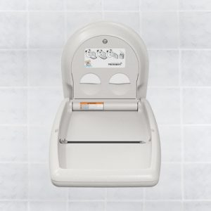 Wall-mounted baby changing station closed against tiled wall, with instructions and illustration.