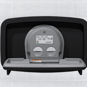 Wall-mounted baby changing station with closed lid and safety strap against tiled background.