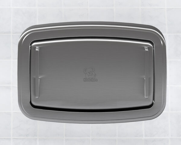 Stainless steel baby changing station on tiled wall, lid closed with logo in center.