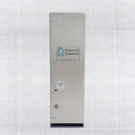 Stainless steel diaper kit dispenser on tile wall with payment slot and purchase instructions.